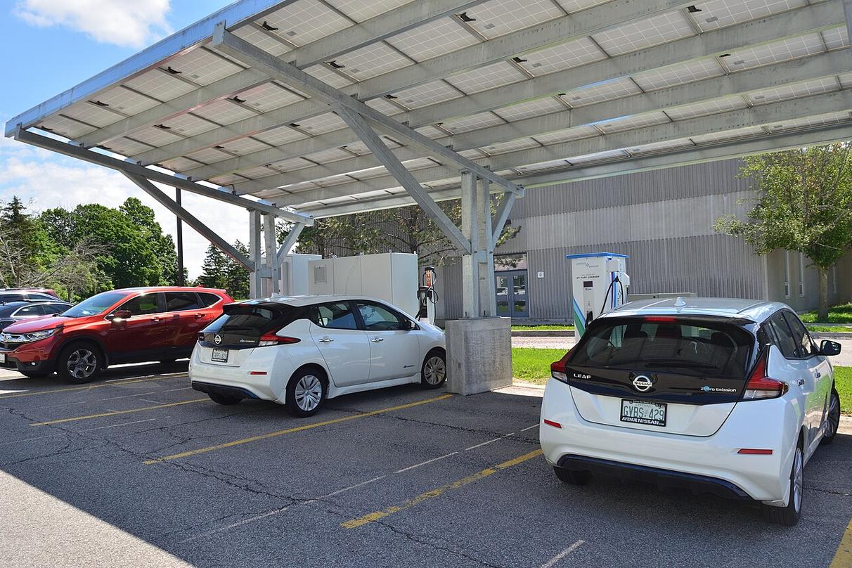 Electric vehicles charging beneath a canopy of solar panels